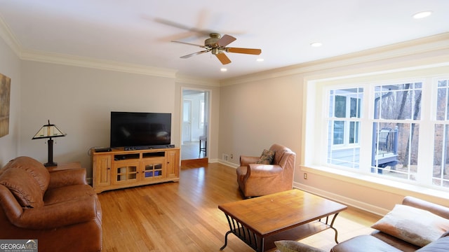 living room with crown molding, ceiling fan, and light wood-type flooring