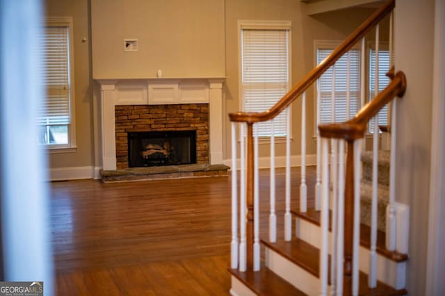 unfurnished living room with a stone fireplace and hardwood / wood-style flooring