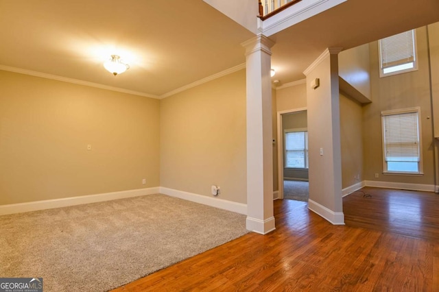 empty room with ornate columns, ornamental molding, a high ceiling, and dark hardwood / wood-style floors