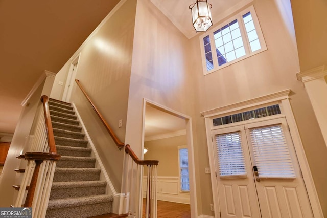 foyer entrance featuring crown molding and a towering ceiling