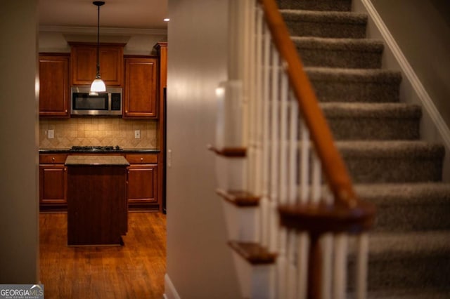 stairs featuring wood-type flooring and ornamental molding