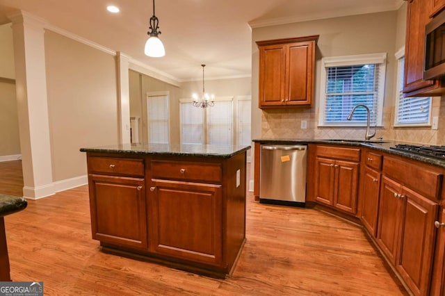 kitchen with a kitchen island, decorative light fixtures, sink, ornamental molding, and stainless steel appliances