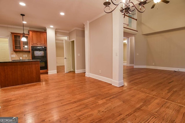 kitchen featuring hanging light fixtures, light hardwood / wood-style flooring, ornamental molding, and black double oven