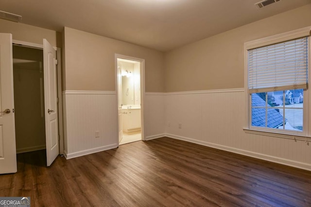 unfurnished bedroom featuring connected bathroom and dark hardwood / wood-style flooring