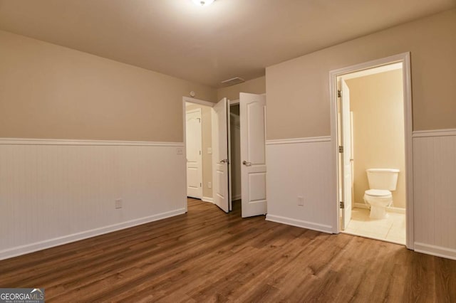 unfurnished bedroom featuring dark hardwood / wood-style flooring and connected bathroom