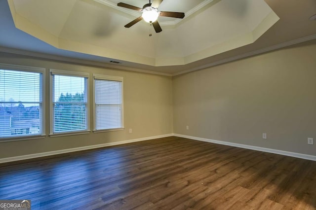 empty room with dark hardwood / wood-style flooring, crown molding, a raised ceiling, and ceiling fan