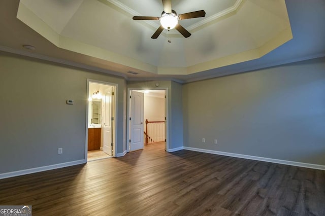 unfurnished bedroom featuring crown molding, dark wood-type flooring, ensuite bath, and a raised ceiling