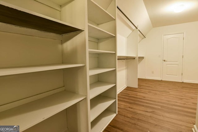 walk in closet with hardwood / wood-style floors and vaulted ceiling