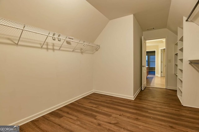 spacious closet featuring lofted ceiling and dark hardwood / wood-style flooring