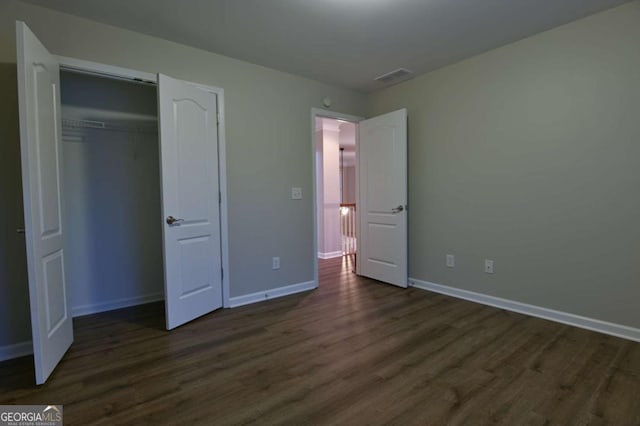 unfurnished bedroom featuring dark hardwood / wood-style flooring and a closet