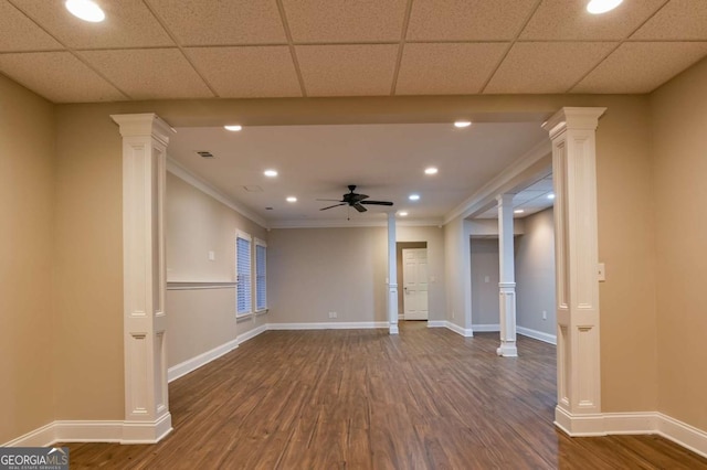 empty room with decorative columns, crown molding, dark hardwood / wood-style floors, and ceiling fan