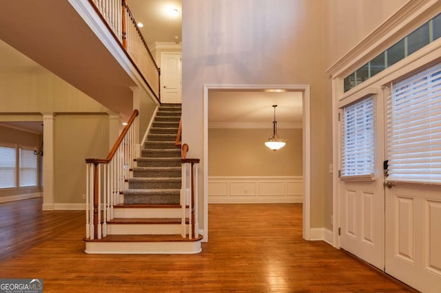 foyer featuring a towering ceiling, ornamental molding, and wood-type flooring