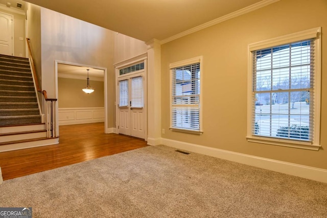 foyer entrance with crown molding, carpet flooring, and a notable chandelier