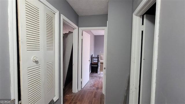 hall with dark wood-type flooring and a textured ceiling