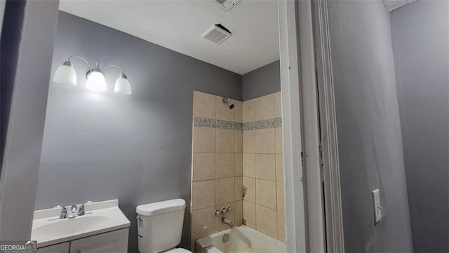 full bathroom with tiled shower / bath, vanity, and toilet