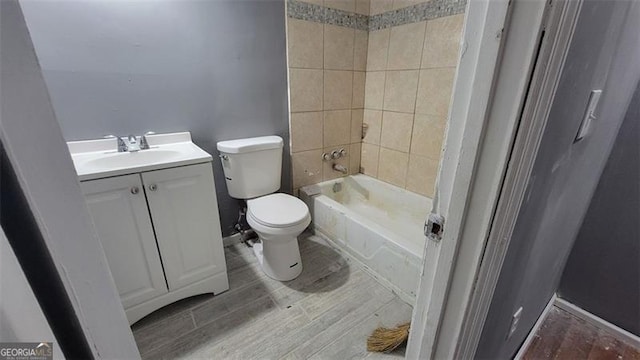 full bathroom with hardwood / wood-style flooring, vanity, tiled shower / bath, and toilet