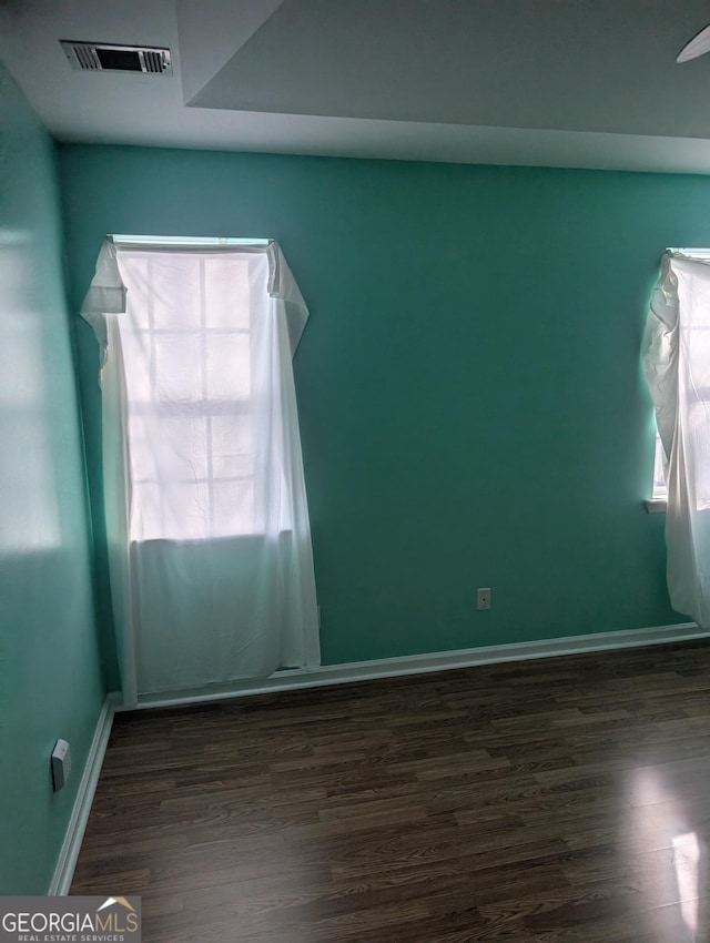 spare room featuring plenty of natural light and dark hardwood / wood-style flooring