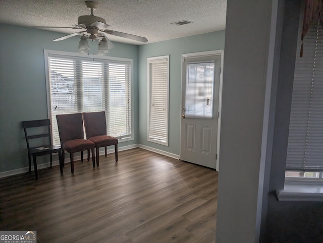 living area featuring dark hardwood / wood-style flooring, ceiling fan, and a textured ceiling