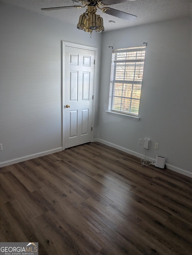 spare room featuring dark hardwood / wood-style flooring, ceiling fan, and a textured ceiling