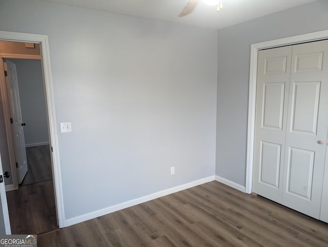 unfurnished bedroom with dark wood-type flooring, ceiling fan, and a closet