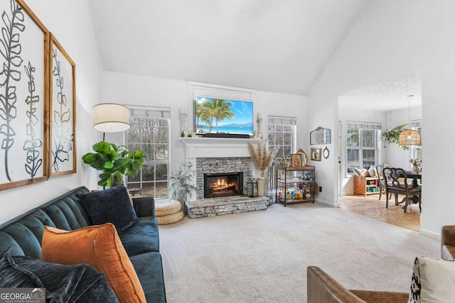 carpeted living room with a stone fireplace and high vaulted ceiling