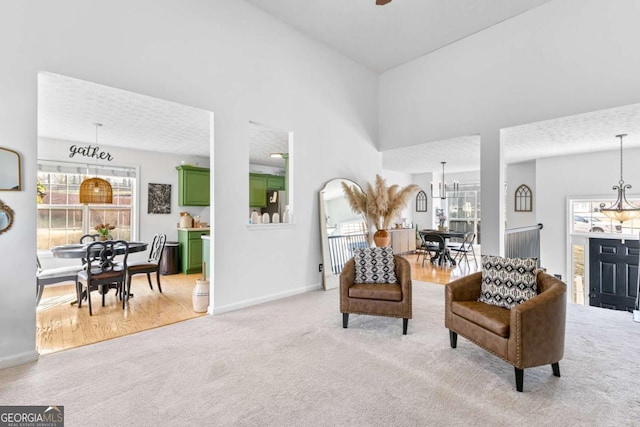 sitting room featuring a towering ceiling, light carpet, and a notable chandelier