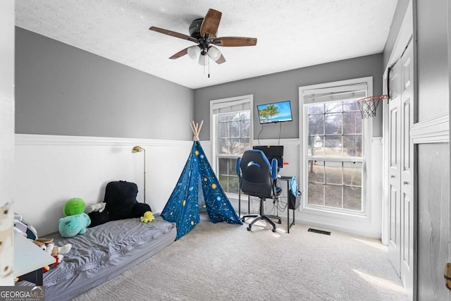 recreation room with ceiling fan, carpet floors, and a textured ceiling