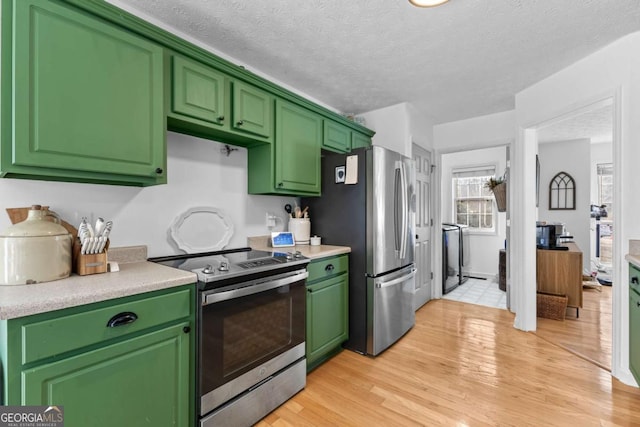 kitchen featuring a textured ceiling, light hardwood / wood-style flooring, green cabinetry, and appliances with stainless steel finishes