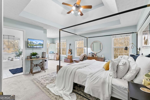 bedroom with a raised ceiling, light carpet, and multiple windows