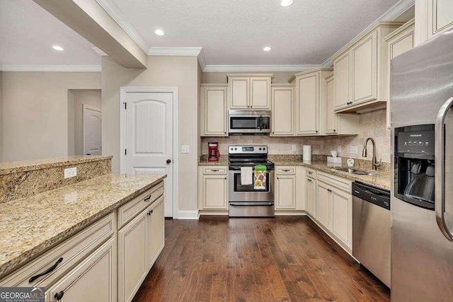 kitchen featuring dark wood-type flooring, sink, light stone counters, stainless steel appliances, and cream cabinets