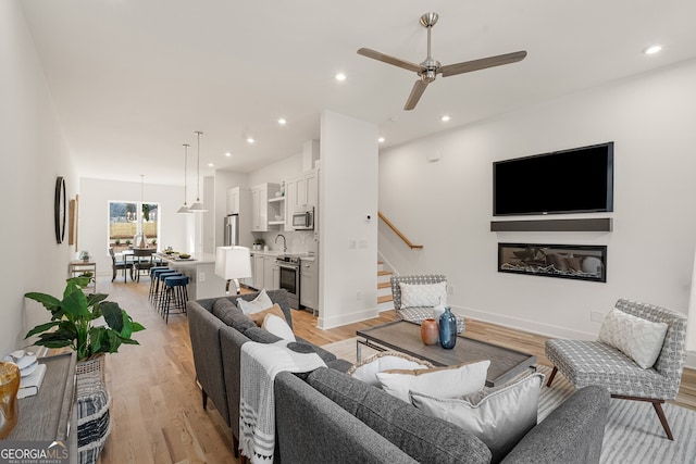 living room with sink, ceiling fan, and light hardwood / wood-style flooring