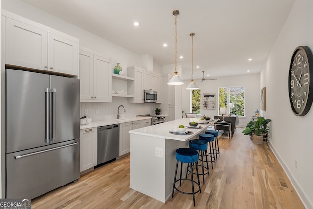 kitchen with pendant lighting, stainless steel appliances, white cabinets, and a kitchen island