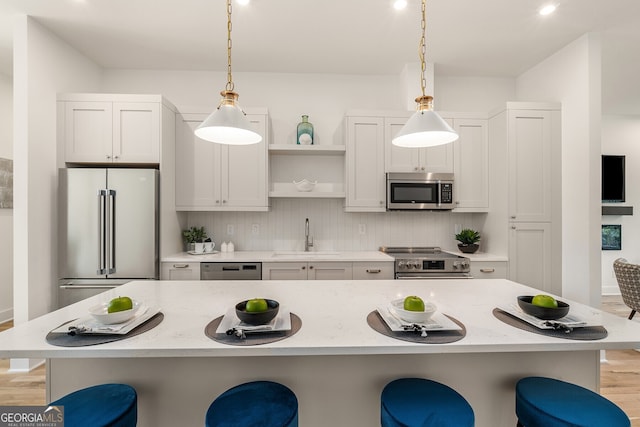 kitchen with white cabinetry, sink, a kitchen bar, and appliances with stainless steel finishes