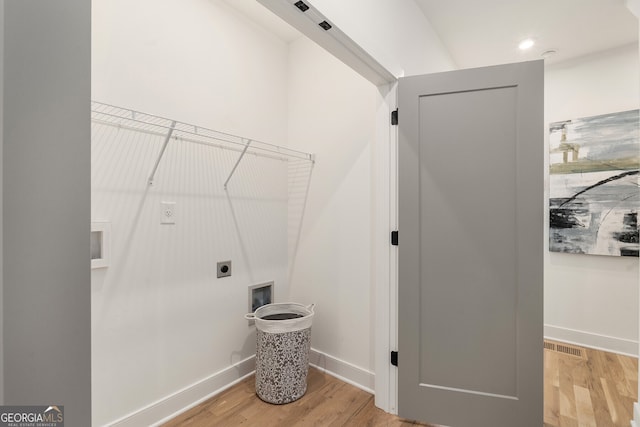 clothes washing area with light hardwood / wood-style floors and hookup for an electric dryer