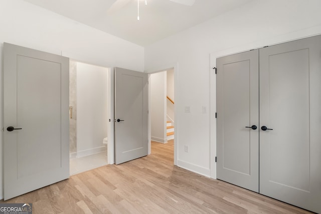 unfurnished bedroom with ensuite bath, a closet, and light wood-type flooring