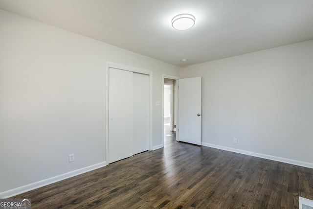 unfurnished bedroom featuring dark hardwood / wood-style flooring and a closet