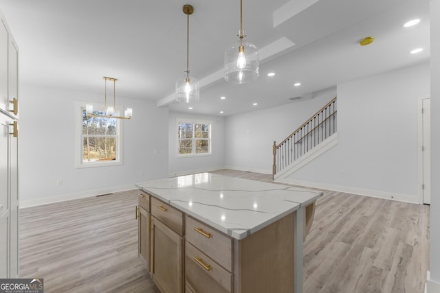 kitchen with pendant lighting, light stone countertops, light hardwood / wood-style floors, and a kitchen island