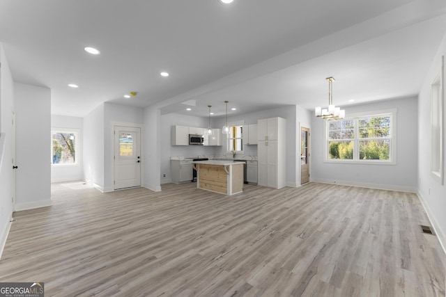 kitchen with a chandelier, a center island, appliances with stainless steel finishes, pendant lighting, and light hardwood / wood-style floors