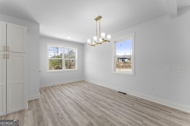 unfurnished dining area with a chandelier and light hardwood / wood-style floors