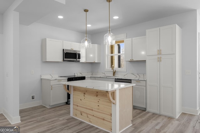 kitchen featuring sink, a breakfast bar, white cabinetry, a center island, and light stone counters