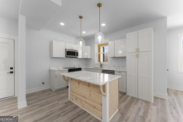 kitchen with decorative light fixtures, white cabinetry, a center island, stainless steel appliances, and light stone countertops