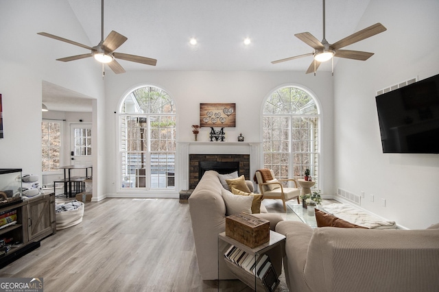 living room with ceiling fan, plenty of natural light, a fireplace, and light hardwood / wood-style flooring