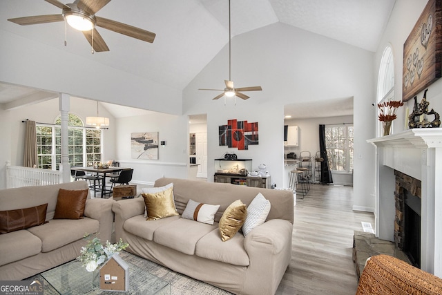 living room with ceiling fan, high vaulted ceiling, and light wood-type flooring