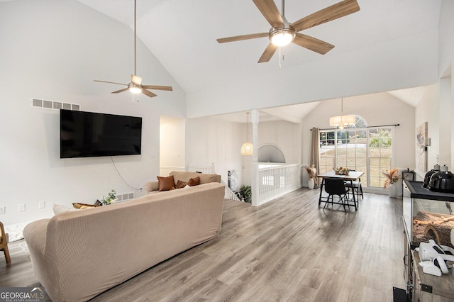 living room featuring hardwood / wood-style flooring, high vaulted ceiling, and ceiling fan with notable chandelier