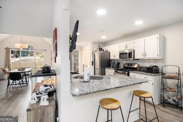 kitchen featuring sink, a breakfast bar area, white cabinets, stainless steel appliances, and light stone countertops