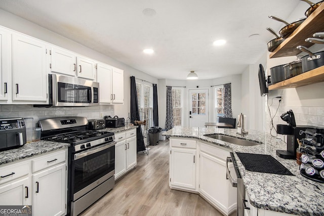 kitchen featuring sink, light hardwood / wood-style flooring, appliances with stainless steel finishes, white cabinetry, and light stone countertops