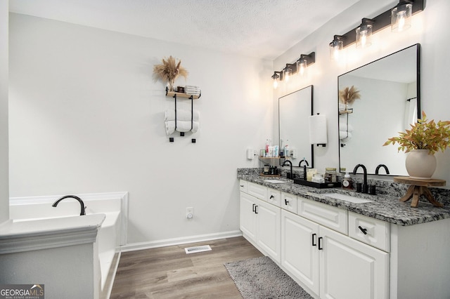 bathroom featuring hardwood / wood-style flooring, vanity, and a textured ceiling