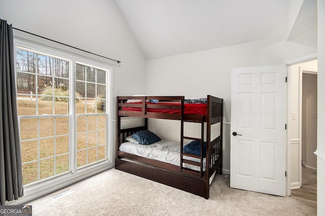 bedroom featuring multiple windows, lofted ceiling, and carpet