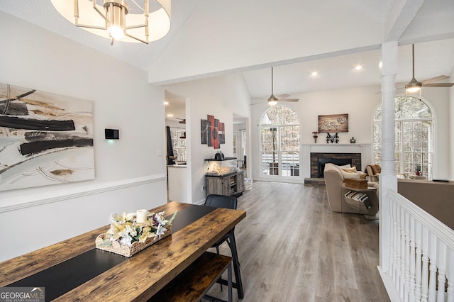 dining space featuring ceiling fan, wood-type flooring, a fireplace, and high vaulted ceiling