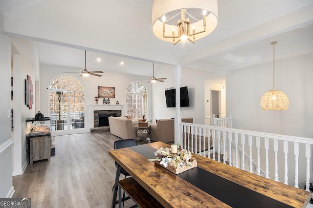 dining space with hardwood / wood-style flooring, a stone fireplace, and an inviting chandelier